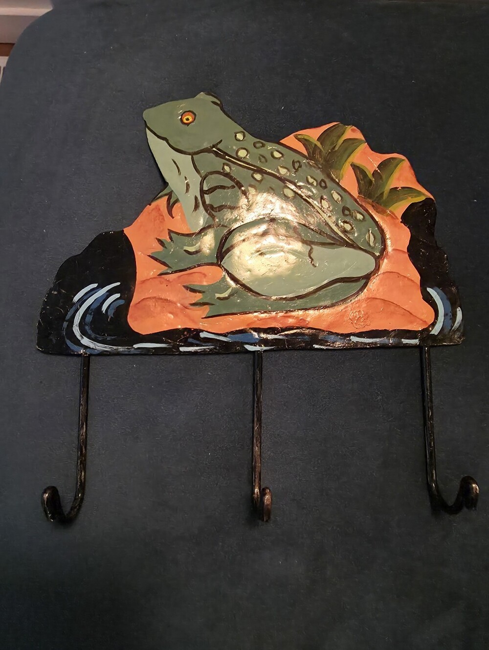 Hand-painted tin wall hook organizer featuring a green frog on a textured orange